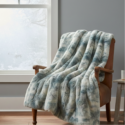 Fluffy blue and white blanket draped over a brown armchair in a room with a window and small table.